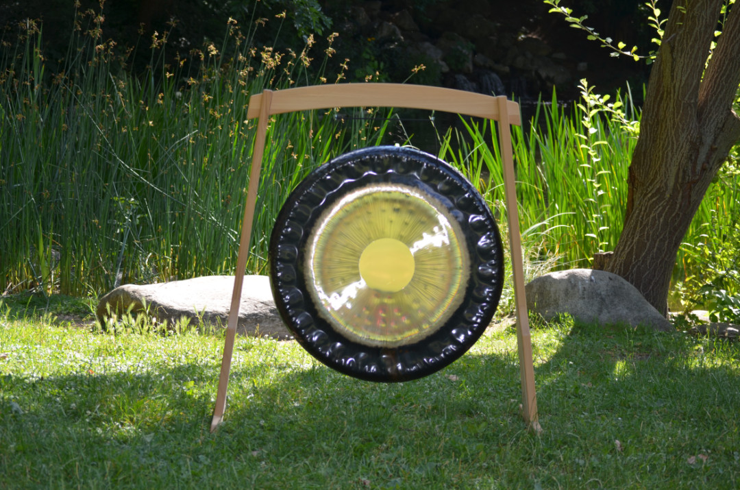 Klangschalen mit Filzschlägel auf einer Wiese, umgeben von Matten und Kissen für eine Klangstunde im Freien
