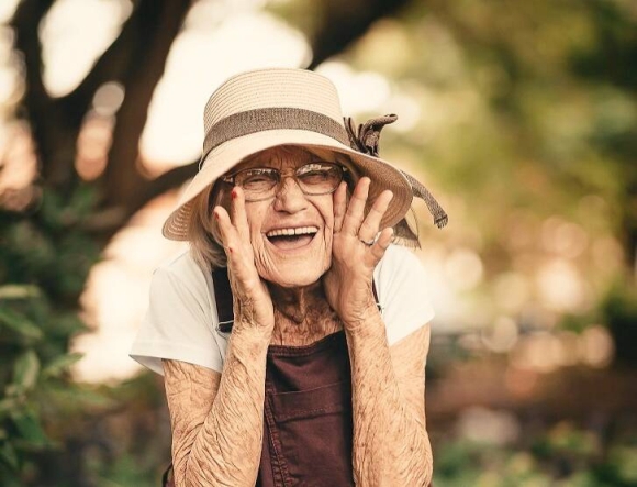 Fröhliche Seniorin mit Sonnenhut lacht herzlich — Lebensfreude und Wohlbefinden